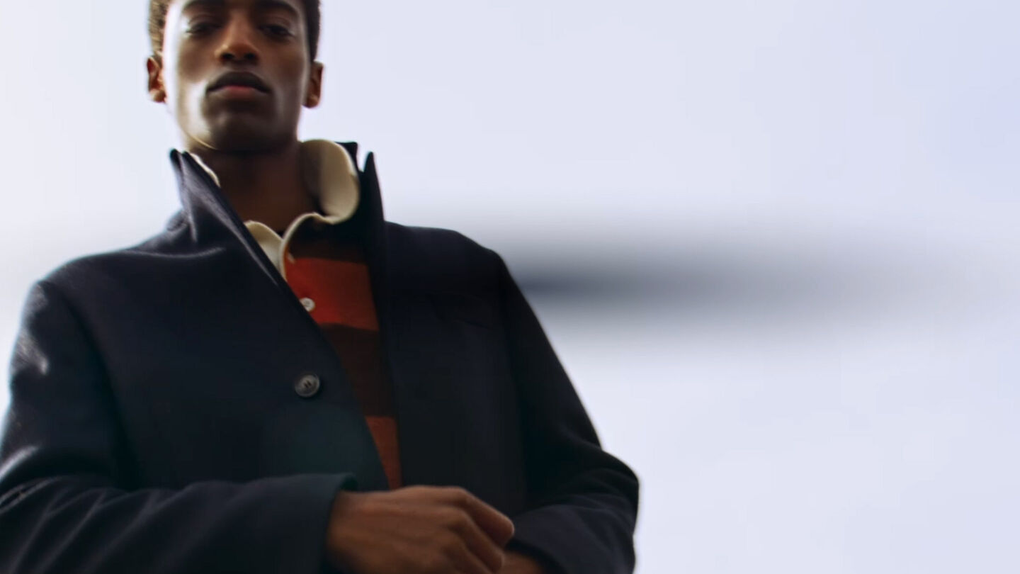 Moving image of a man wearing Classic Wool Coat in evening blue and Barstriped rugger in color golden orange